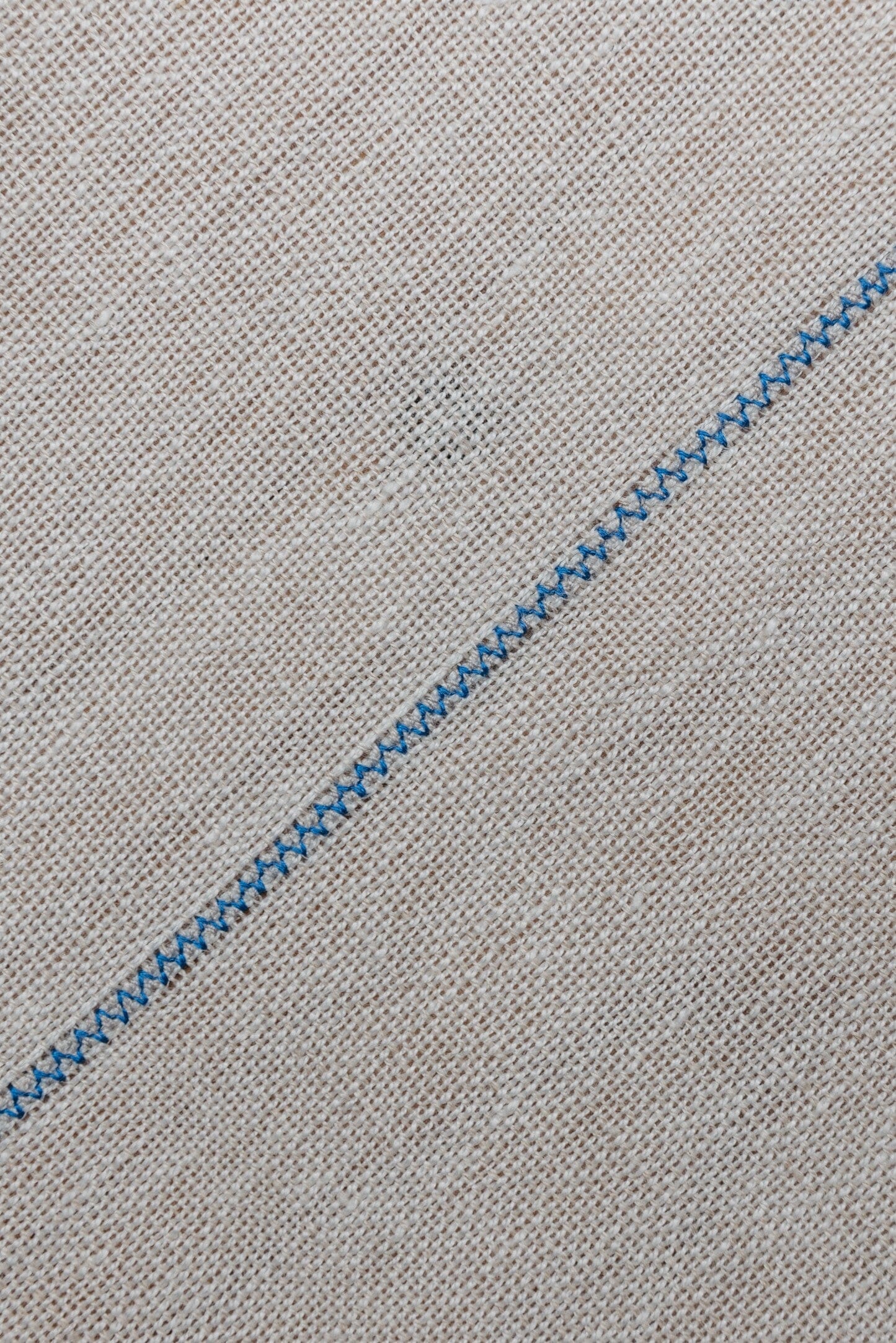 Detalle de mantel artesanal de lino blanco con uniones azules, hecho a mano en España por ÁBBATTE