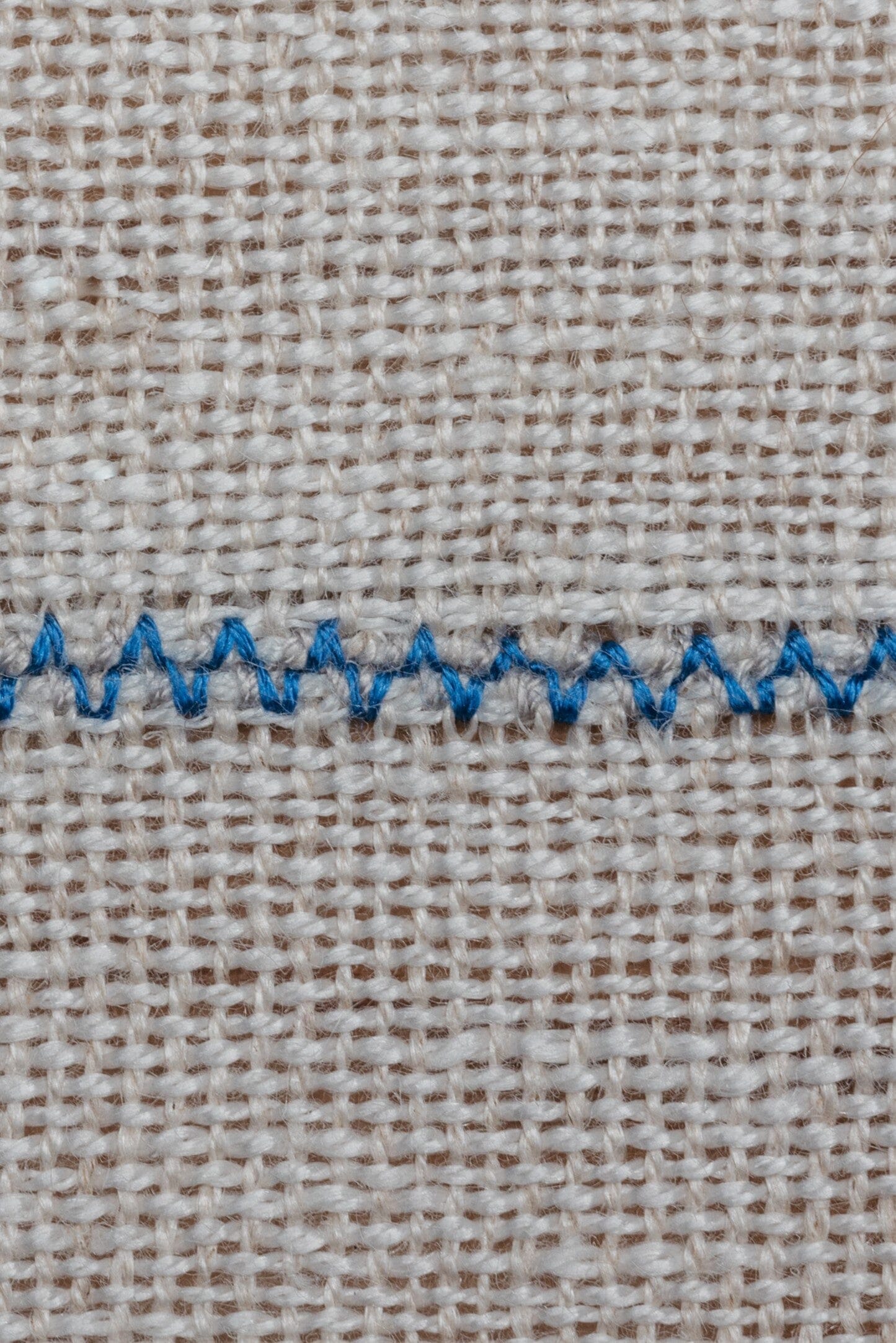 Detalle de mantel artesanal de lino blanco con uniones azules, hecho a mano en España por ÁBBATTE